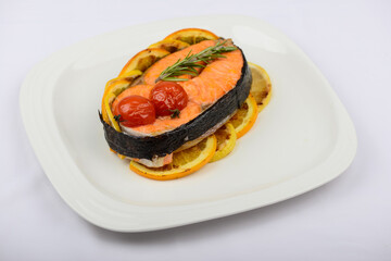 baked salmon fillet with tomatoes and herbs on a white plate