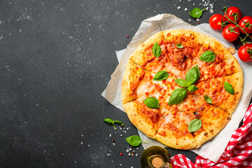 Pizza margarita on black background with ingredients for cooking.