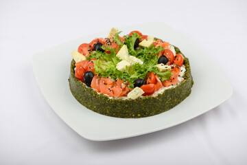 spinach pie with cheese, herbs and tomatoes on a white plate on a background