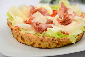 pie with bacon and herbs and tomatoes on a white plate macro photo