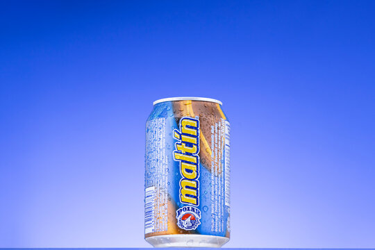 Cold can with water droplets.of Malt&iacute;n Polar, a non-alcoholic Venezuelan malt or root beer beverage, isolated over a blue gradient background.