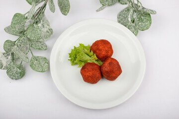 Cheese balls in batter on a white plate on a background with decor