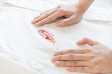 Dirty sauce stain cloth, housewife asian young woman holding white shirt, showing making cloth stain, spot dirty or smudge on clothes for cleaning before washing, maid female working at home concept.