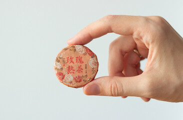 hand holding a package of traditional chinese tea with flowers in a compressed form isolated on white