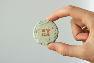 hand holding a package of traditional chinese white tea for tea ceremony. The tea comes in a...