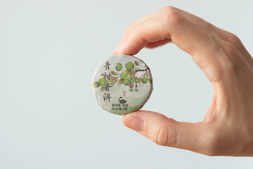 hand holding a package of traditional compressed chinese tea for tea ceremony isolated on white