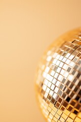 Close-up of shiny gold disco ball featuring mirror tiles, reflective surface, soft blurred background