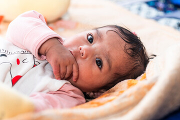 A cute Indonesian baby in warm clothes lying on a colorful blanket. Perfect for themes of...