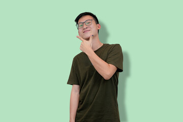 Casual young man making a playful pose with light green background
