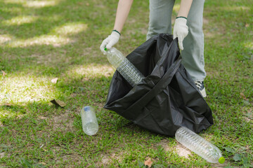 Person Picking Up Plastic Bottles in Park