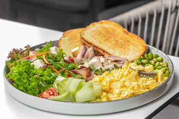 A hearty and colorful breakfast platter with fluffy scrambled eggs, roast beef, cheese, fresh...