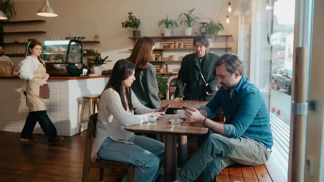 Customers enter the cafe and sit at a table, a female employee approaches them to take their order