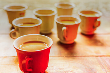 A vibrant collection of traditional Masala Chai cups, including a prominent red mug, rests on a warm wooden surface, perfect for capturing cozy moments and authentic Indian tea.