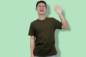 Casual young man making a playful pose with light green background
