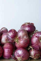Bunch red onions with white wall background in vertical. Close-up old skin of onion with copy...