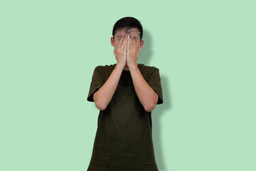 Young Man in Casual Outfit in Deep Thought Against Green Background