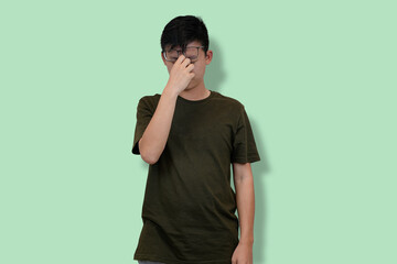 Young Man in Casual Outfit in Deep Thought Against Green Background
