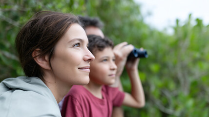 Family exploring wildlife sanctuary with binoculars, smiling and enjoying nature together outdoors in lush green forest