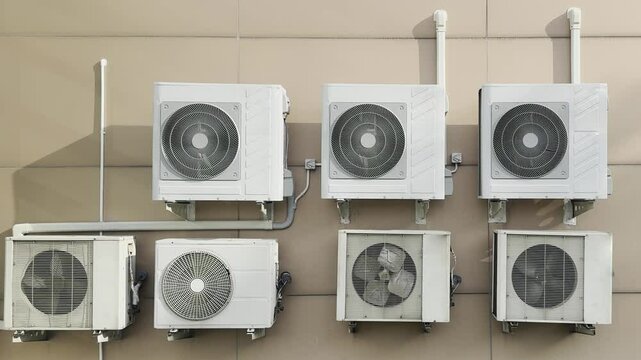 Group of outdoor AC condensing units operating on a high-rise building wall for centralized cooling, short footage.