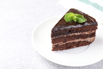 Piece of delicious chocolate cake with mint on grey table, closeup. Space for text