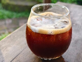 A round refreshing glass filled with iced black coffee