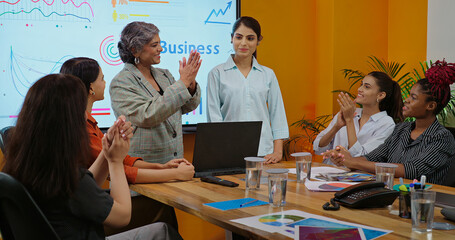 Indian happy senior boss woman project manager young adult expert girl lady get work indoor job office Asian smiling proud leader talk hiring new intern staff join group team clap hands at place