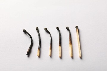 Burnt matches on light grey background, closeup