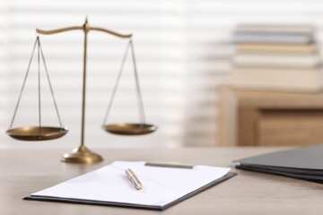 Judge. Scales, clipboard, pen and folders on wooden table in office, selective focus