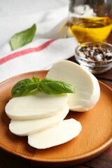 Tasty mozzarella, tomatoes and basil on wooden table, closeup