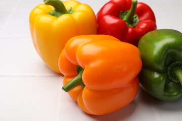 Fresh colorful bell peppers on white table, closeup
