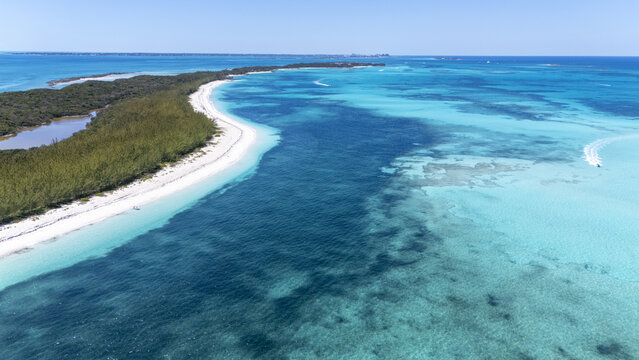 Aerial view of the vibrant turquoise waters contrast with the white sandy beach and lush greenery of Black Point, New Providence, The Bahamas.