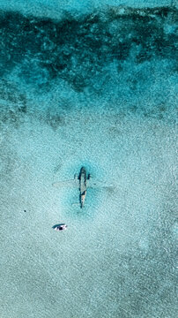 Aerial view of  Pablo Escobar plane sank   in  the turquoise waters, the Bahamas, creating ripples in the serene ocean surface, Black Point, Black Point, The Bahamas.