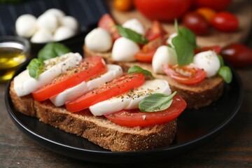 Tasty sandwiches with mozzarella cheese, tomatoes, basil and spices on wooden table, closeup