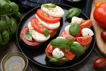 Tasty sandwiches with mozzarella cheese, tomatoes, basil and spices on wooden table, closeup