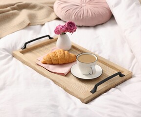 Tray with delicious breakfast and flowers on bed indoors, closeup