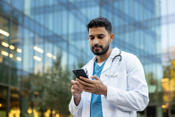 A doctor in a white coat uses a phone, set against a modern building exterior. He seems focused on...