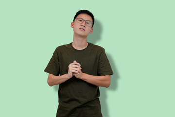 Young Man Standing With Clasped Hands Against a Pastel Green Background