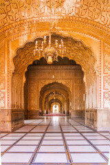 Fototapeta premium Experience the rich heritage within Badshahi Mosque, where ornate frescoes, grand archways, and a sparkling chandelier create an atmosphere of profound beauty and architectural mastery.