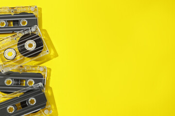 Audio cassettes with magnetic tapes on yellow background, flat lay. Space for text