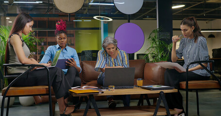 Indian busy old aged boss lady sitting on sofa couch use on desk table laptop look screen do work...