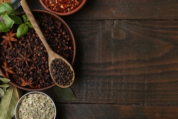 Different aromatic spices on wooden table, flat lay. Space for text