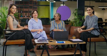 Indian young adult woman talk gossip with old aged boss ceo lady enjoy day spend time job place happy smiling female girl expert staff team leader speak talk share good news do new work deal at office