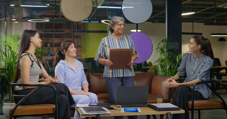 Indian old aged boss lady hold file do share good news new deal work talk speak ideas plan job...