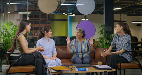 Indian young adult woman talk gossip with old aged boss ceo lady enjoy day spend time job place happy smiling female girl expert staff team leader speak talk share good news do new work deal at office