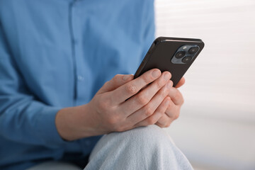 Woman using modern smartphone at home, closeup