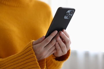 Woman using modern smartphone at home, closeup