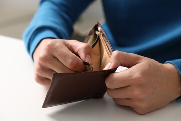 Man with empty wallet at white table, closeup