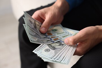 Man counting his money indoors, closeup view