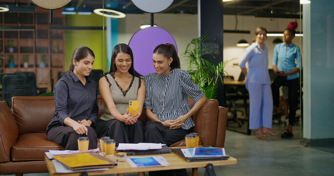 Indian young adult young adult woman lady hold mobile look cam talk gossip on video call at work place happy female girl staff use phone speak distant enjoy break spend time have fun joy job office - Powered by Adobe