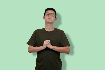 Young Man Standing With Clasped Hands Against a Pastel Green Background